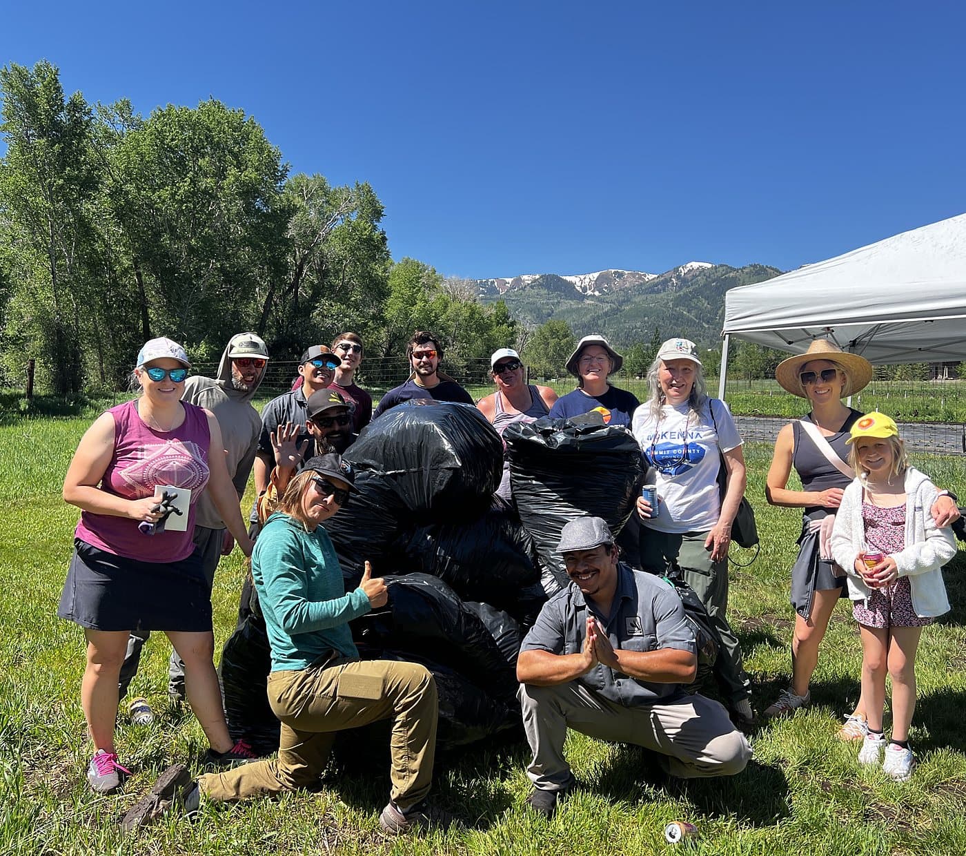 A crowd of Garlic Mustard Games volunteers behind their bagged haul, mountains in the distance